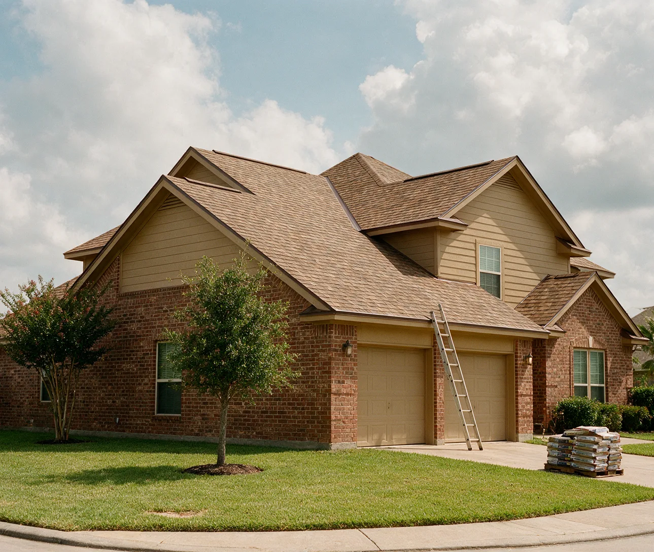Two-storey brick house in Missouri City with a newly finished brown shingle roof, a ladder at the garage and leftover bundles on the driveway